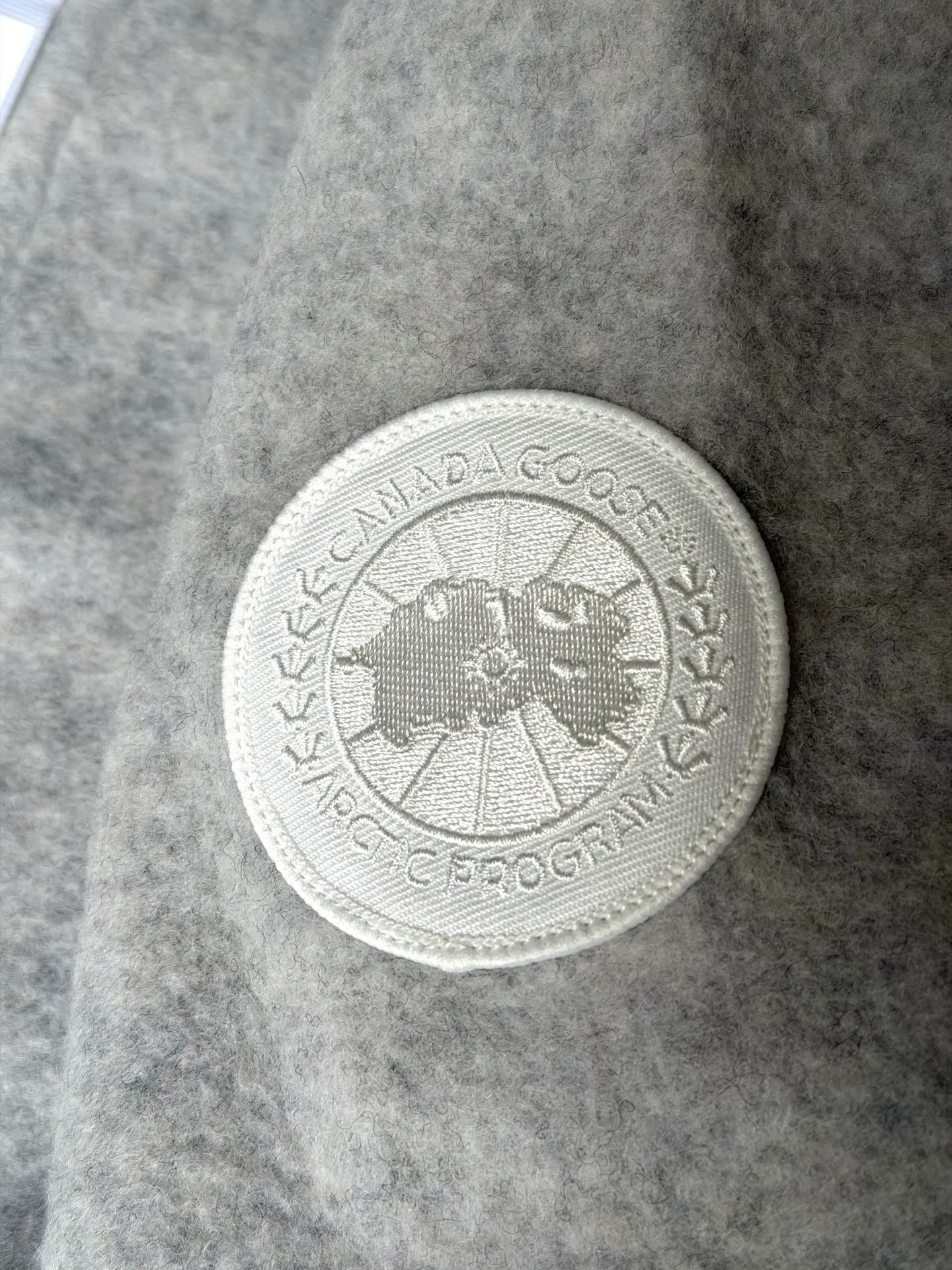 P620 Canada Goose Fleece Wool Baseball Jacket Fabric selection: Wool fleece fabric blended with wool as the main body and a very small amount of spandex and polyester fiber. Wool is a core natural ingredient that provides unparalleled temperature regulation, antibacterial and anti-odor properties and a skin-friendly feel. The feeding of a small amount of spandex gives the fabric a certain degree of four-way elasticity, making it non-restrictive during daily activities. As the basis of fleece's structure, polyester fiber enhances the fabric's durability, wrinkle resistance and quick-drying properties. It contributes to the loft of the fleece and provides functions such as trapping air.  Detail 1: The sleeves and hem are closed with 2×2 ribbing. Its strong elasticity can closely fit wrists and waists of different thicknesses, forming an effective 'seal' to prevent cold wind from blowing back. It can still maintain its original shape after repeated stretching and use, and is not easy to loose and deform. And the ribbed cuffs can convey a sense of design and enhance the visual beauty.  Detail 2: The combination of hood design and elastic buckle improves warmth and windproof performance when wearing. Accessories: Customized elastic drawstring, elastic buckle, custom zipper pendant, custom armband Size: S M L Color: Black Gray Mickey